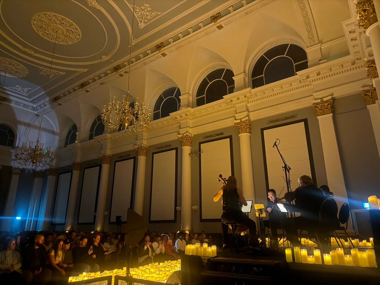 Weddington Strings performing on the candlelit stage at Rochester Corn Exchange, with the audience seated alongside