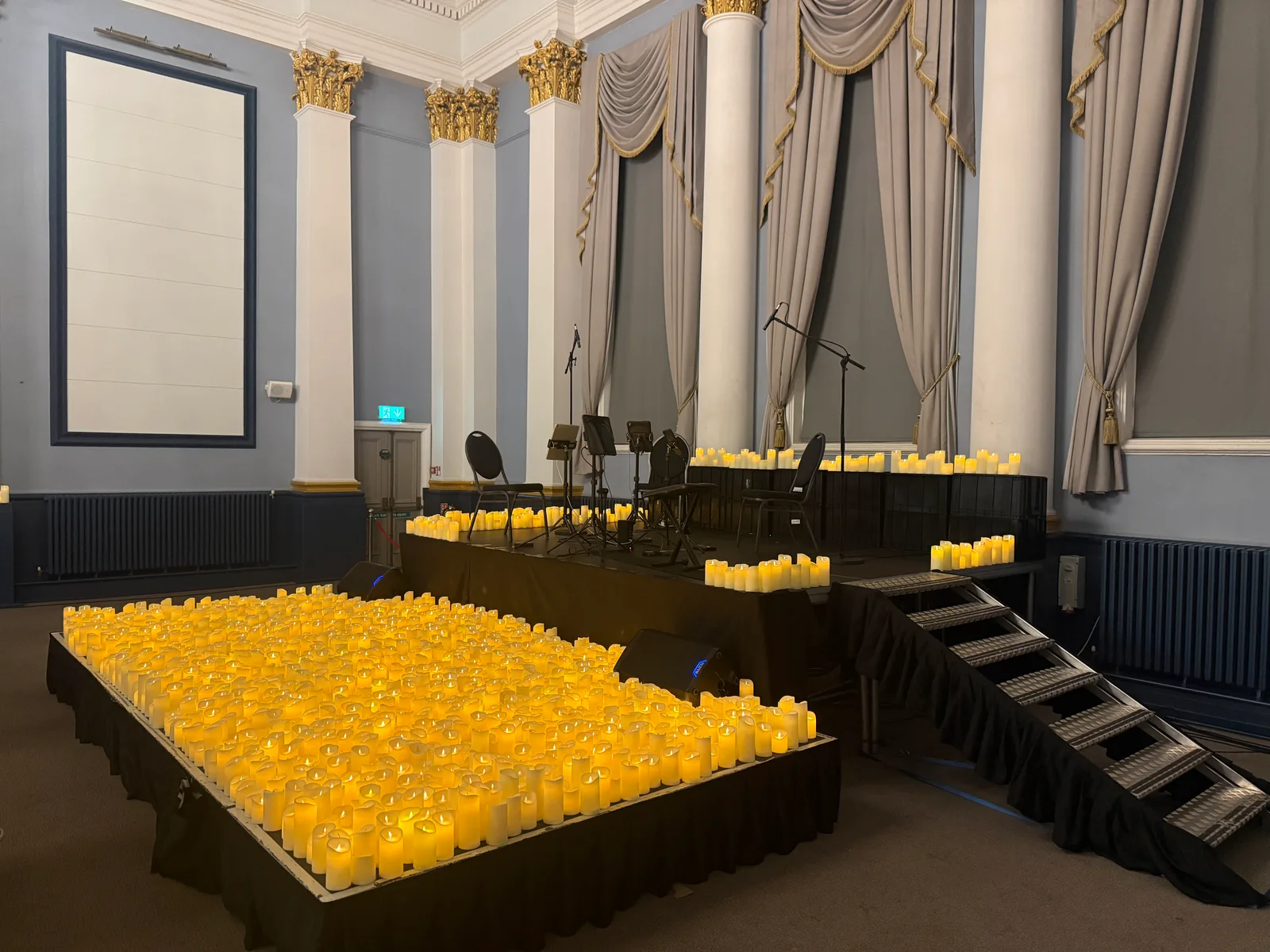 The completed stage at Rochester Corn Exchange with microphones, chairs, stage steps and the Candlelight candle display