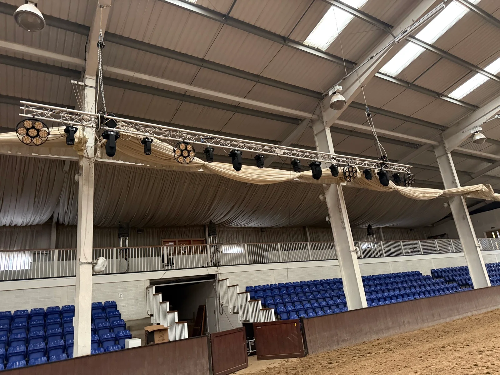 Overhead lighting fixtures installed across the indoor riding arena before the event